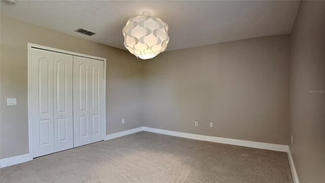 unfurnished bedroom featuring light colored carpet and a closet