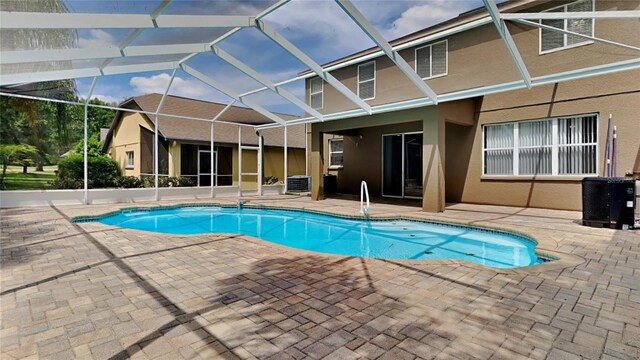 view of pool with glass enclosure, central AC unit, and a patio