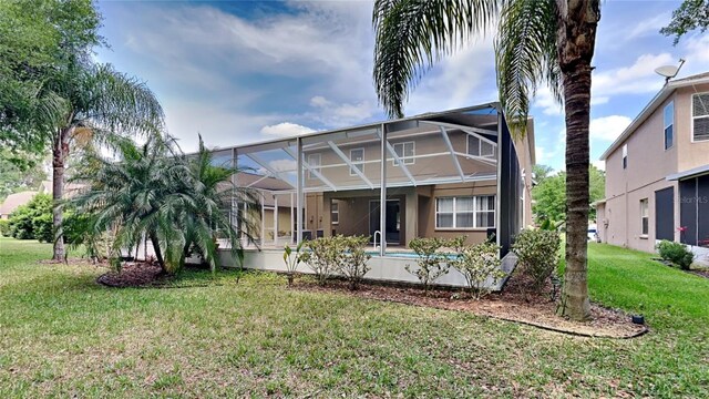 rear view of property with glass enclosure and a yard