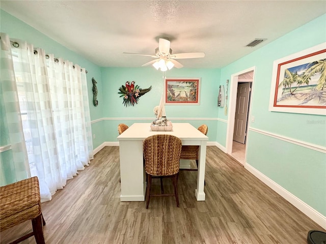 dining area with hardwood / wood-style floors, ceiling fan, and a textured ceiling