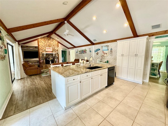 kitchen featuring white cabinets, black dishwasher, sink, and a kitchen island with sink