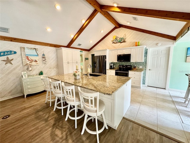 kitchen with a large island with sink, white cabinets, black electric range oven, and lofted ceiling with beams