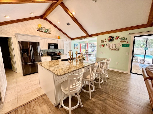 kitchen featuring black appliances, white cabinets, a spacious island, sink, and a breakfast bar area