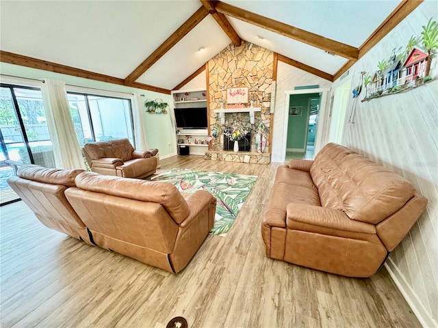 living room featuring hardwood / wood-style floors, lofted ceiling with beams, a stone fireplace, and built in shelves