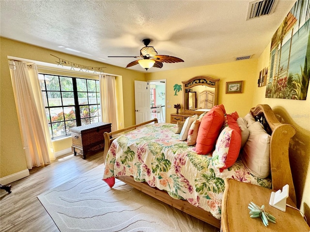 bedroom with hardwood / wood-style flooring, ceiling fan, and a textured ceiling