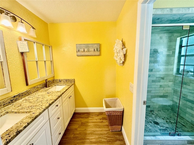 bathroom featuring vanity, a shower with shower door, a textured ceiling, and hardwood / wood-style flooring