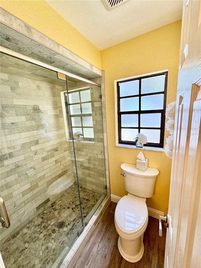 bathroom with a shower with door, wood-type flooring, a textured ceiling, and toilet