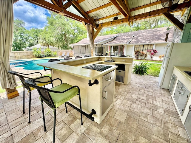 view of patio featuring exterior bar, a gazebo, a fenced in pool, and exterior kitchen