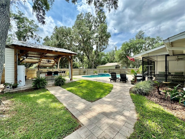 view of yard with exterior bar, a gazebo, a sunroom, a patio, and a fenced in pool