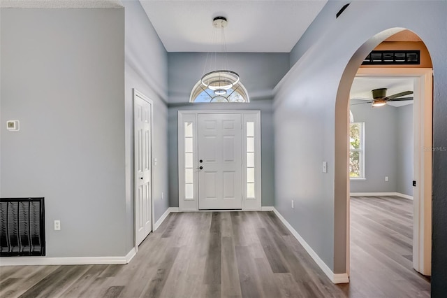 entryway with ceiling fan with notable chandelier and light hardwood / wood-style flooring