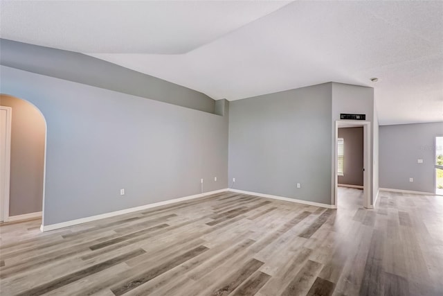 empty room with light hardwood / wood-style floors and vaulted ceiling