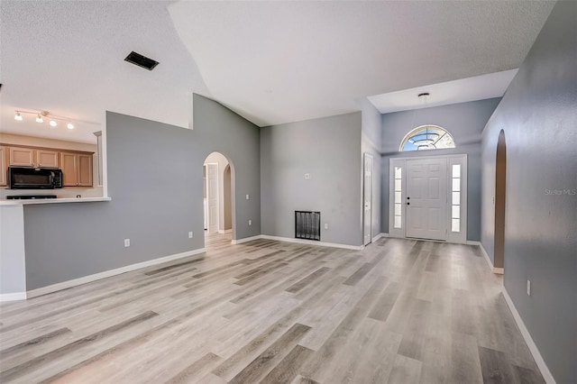 unfurnished living room with light wood-type flooring, rail lighting, and a textured ceiling