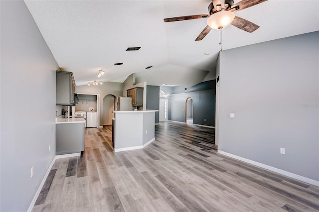 kitchen featuring ceiling fan, gray cabinets, light hardwood / wood-style flooring, stainless steel refrigerator, and vaulted ceiling