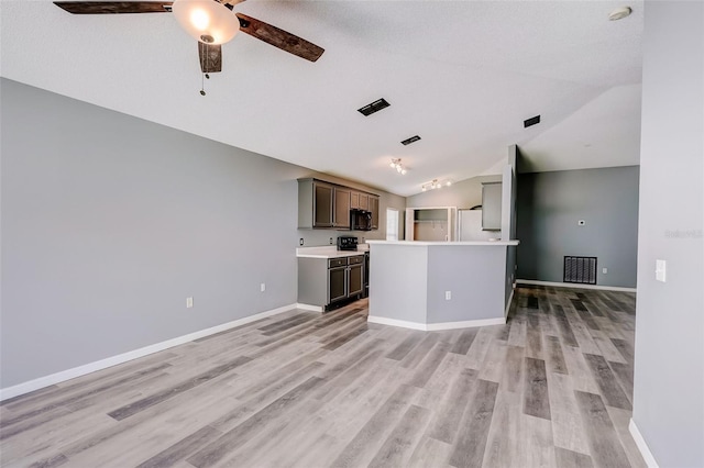 kitchen featuring ceiling fan, white fridge, a kitchen island, light hardwood / wood-style floors, and vaulted ceiling