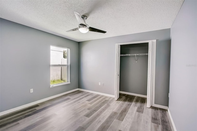 unfurnished bedroom with a closet, a textured ceiling, ceiling fan, and light wood-type flooring