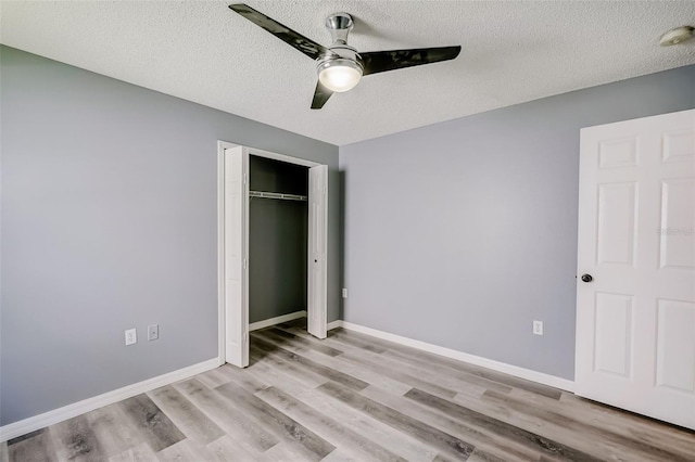 unfurnished bedroom with a closet, a textured ceiling, ceiling fan, and light hardwood / wood-style flooring