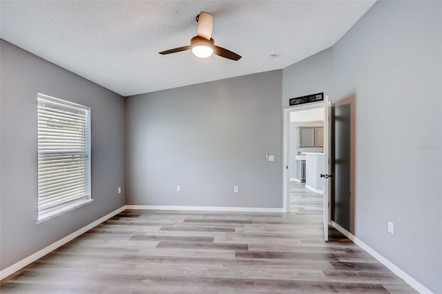 unfurnished room with a healthy amount of sunlight, vaulted ceiling, ceiling fan, and light wood-type flooring