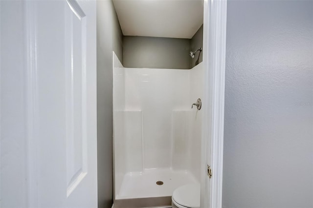 bathroom featuring walk in shower and toilet