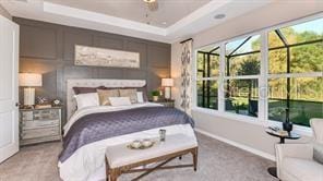 carpeted bedroom featuring ceiling fan, a tray ceiling, and multiple windows