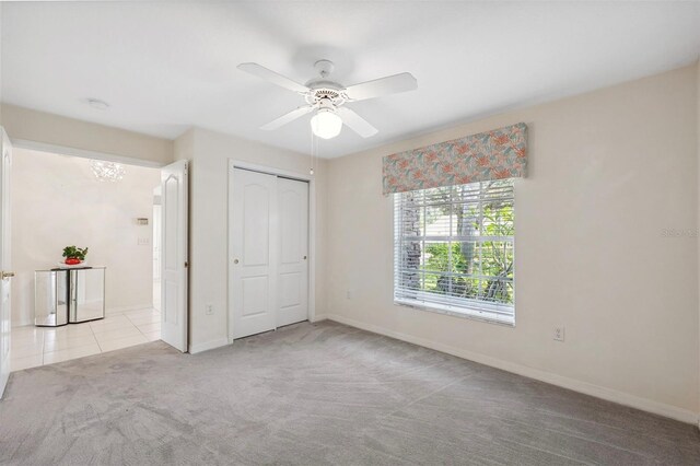 unfurnished bedroom featuring a closet, light colored carpet, and ceiling fan