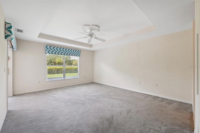 carpeted empty room featuring a raised ceiling and ceiling fan