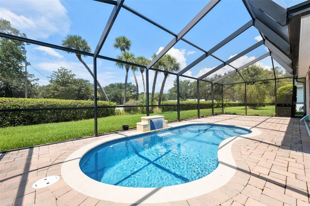 view of pool with a patio area, pool water feature, a yard, and glass enclosure