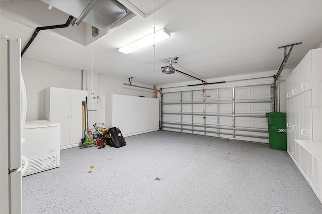 garage featuring white refrigerator and a garage door opener