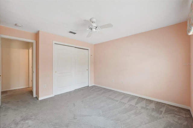 unfurnished bedroom featuring a closet, light colored carpet, and ceiling fan