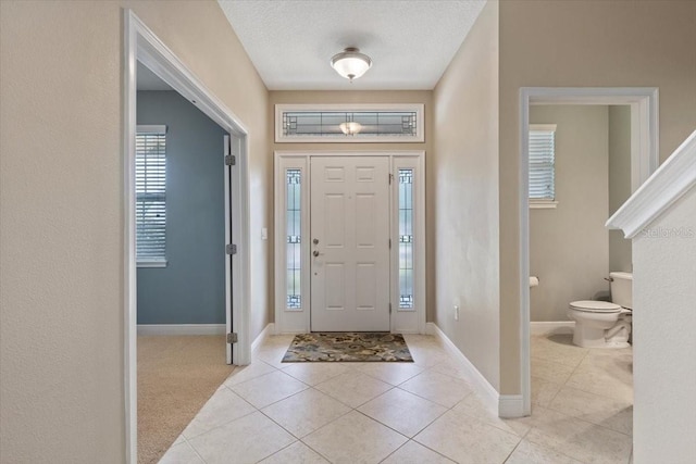 foyer with a textured ceiling and light tile patterned floors