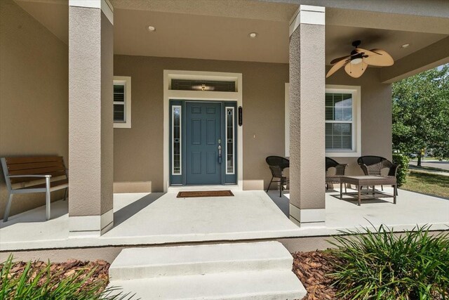 entrance to property featuring covered porch and ceiling fan