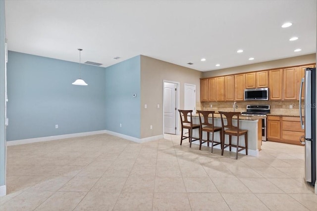 kitchen featuring stone counters, a breakfast bar area, decorative backsplash, hanging light fixtures, and appliances with stainless steel finishes