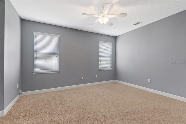 carpeted empty room with ceiling fan and a healthy amount of sunlight