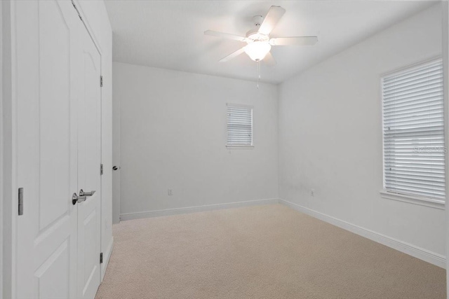 spare room with ceiling fan and light colored carpet