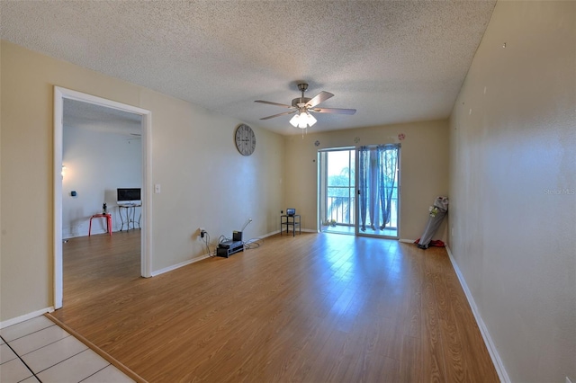 unfurnished room with ceiling fan, a textured ceiling, and light wood-type flooring