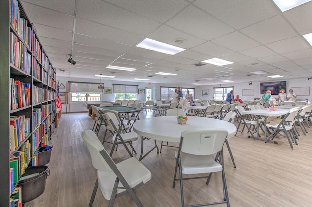 dining room with hardwood / wood-style flooring, a healthy amount of sunlight, and a drop ceiling