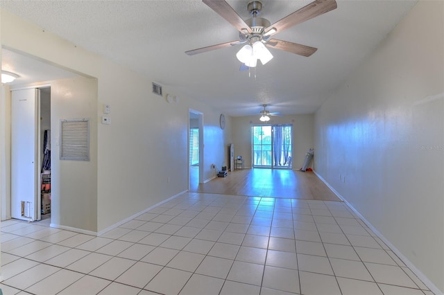 unfurnished room with a textured ceiling, ceiling fan, and light tile patterned floors