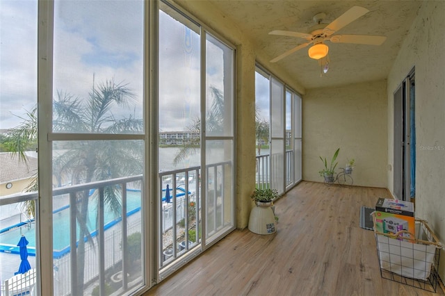 sunroom / solarium with ceiling fan, a water view, and a wealth of natural light