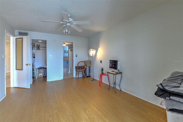 miscellaneous room featuring a textured ceiling, ceiling fan, and light hardwood / wood-style floors