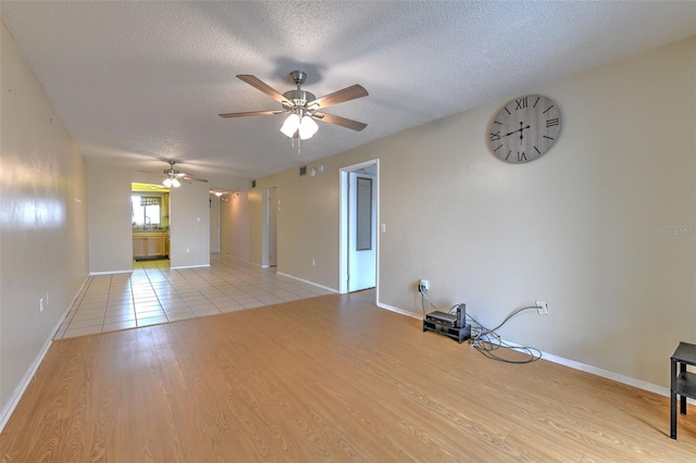 spare room with light wood-type flooring, ceiling fan, and a textured ceiling