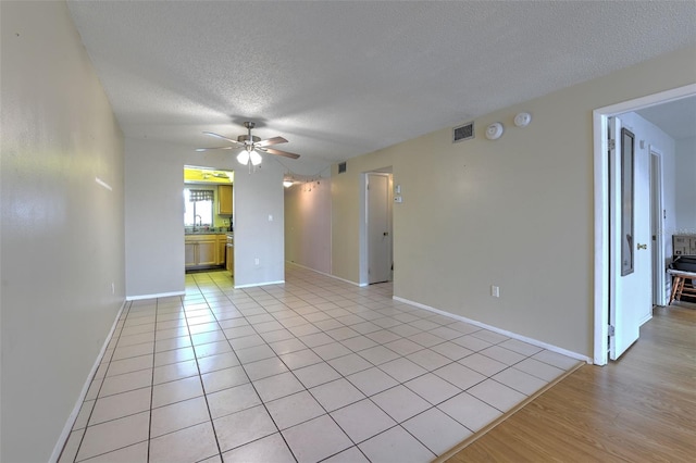 tiled empty room with ceiling fan and a textured ceiling