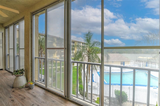 unfurnished sunroom with ceiling fan and a water view