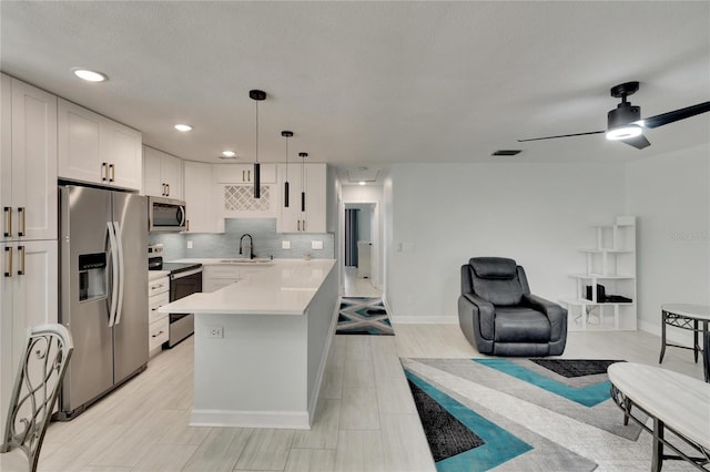 kitchen featuring appliances with stainless steel finishes, hanging light fixtures, ceiling fan, tasteful backsplash, and white cabinets