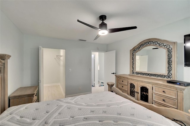 bedroom featuring ceiling fan, a closet, a walk in closet, and light wood-type flooring