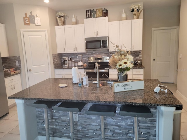 kitchen featuring appliances with stainless steel finishes, white cabinetry, and a breakfast bar area