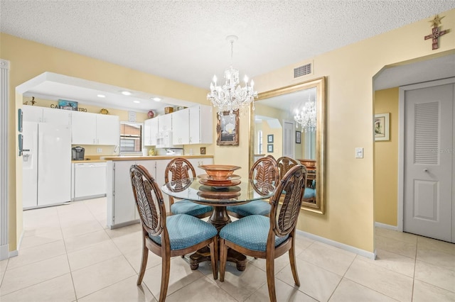 tiled dining space featuring a textured ceiling and an inviting chandelier