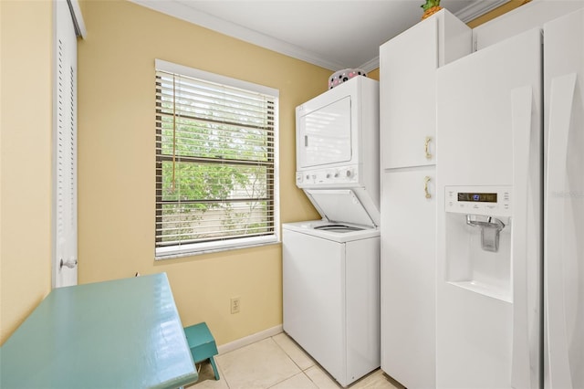 clothes washing area with cabinets, stacked washer / dryer, crown molding, and light tile flooring