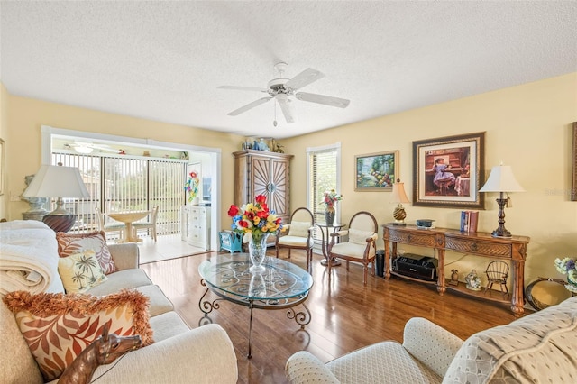 living room with hardwood / wood-style flooring, ceiling fan, and a textured ceiling