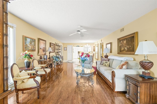 living room featuring ceiling fan, dark wood-type flooring, and a textured ceiling