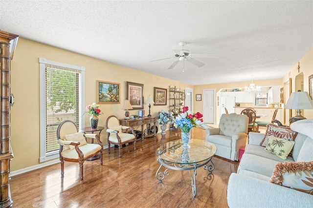 living room featuring ceiling fan with notable chandelier, a textured ceiling, and hardwood / wood-style floors