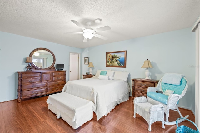 bedroom with dark hardwood / wood-style flooring, ceiling fan, and a textured ceiling